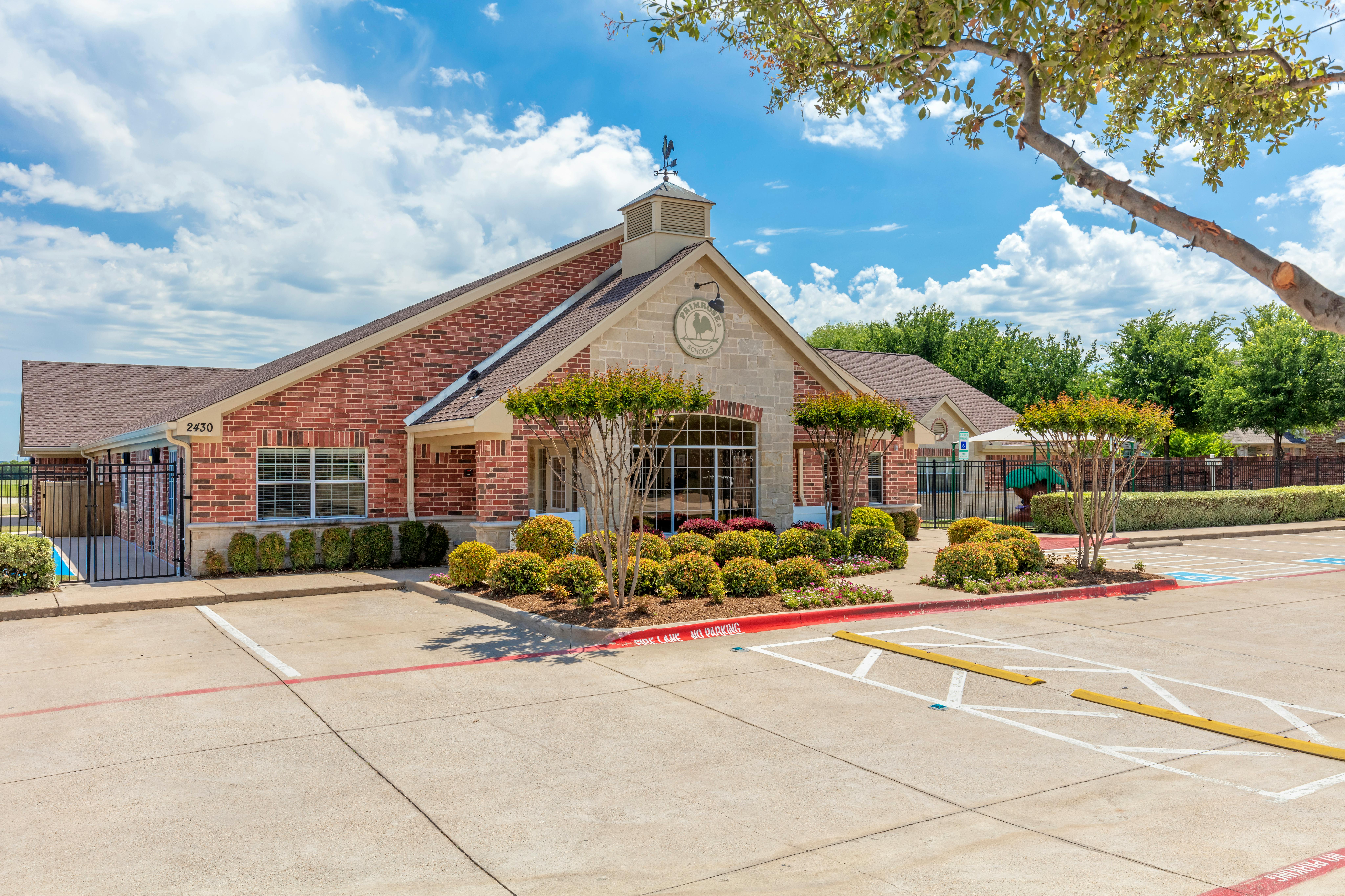 Brick building with a stone facade, cupola, and a sign that reads "Primrose Schools"