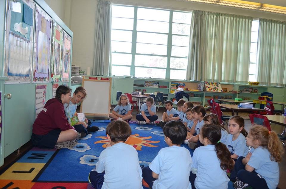 Adults and children sitting on a rug in a classroom