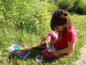 Child sitting in grass and drawing