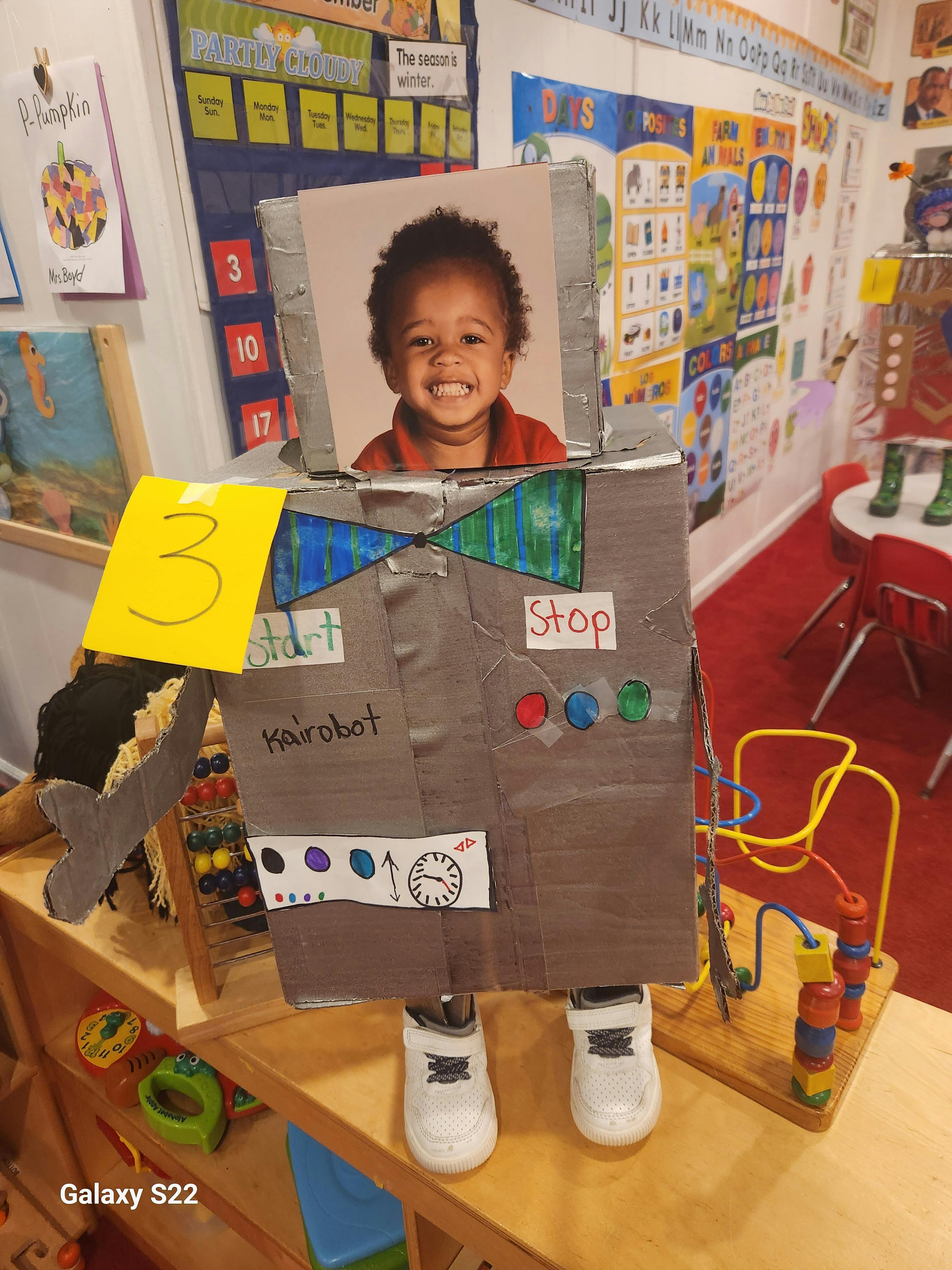 Cardboard robot with a child's photo for a head, text "Harobot" and "Stop"