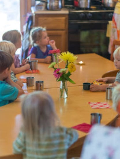 Children sitting around a table with flowers in the center