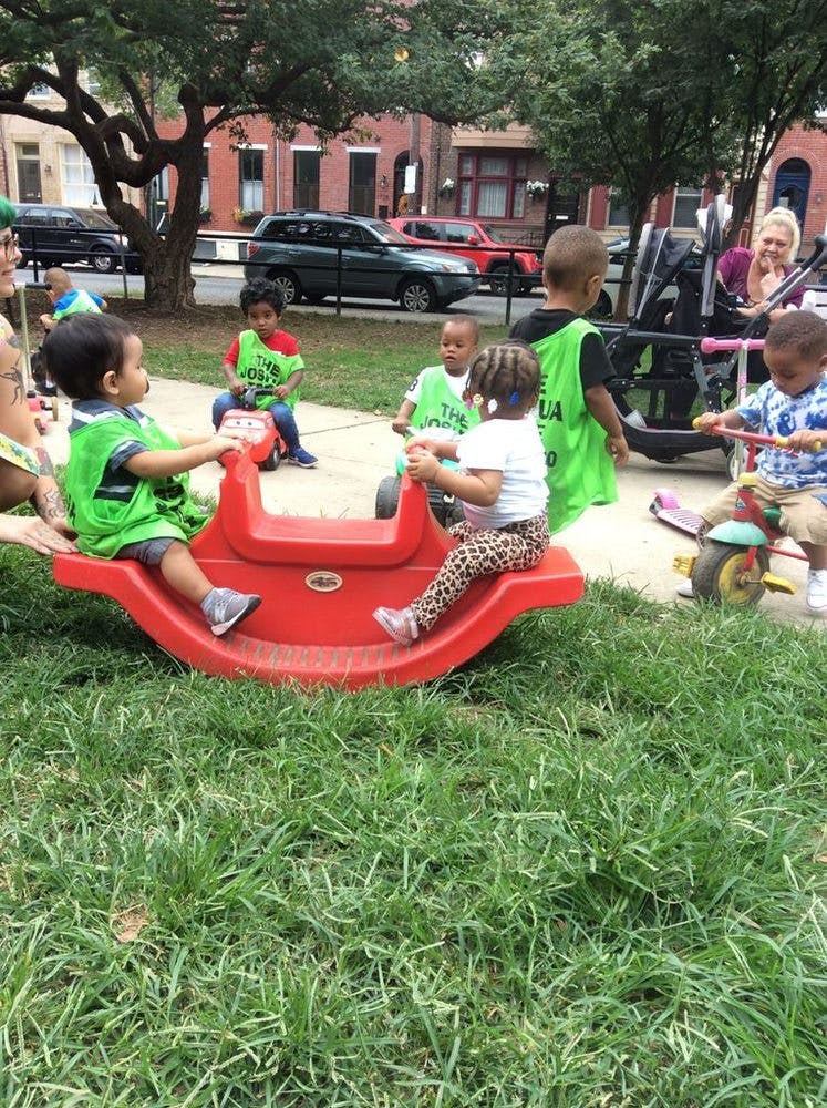 Children playing on a red seesaw and riding toys outdoors