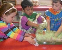 Three children playing with green dough