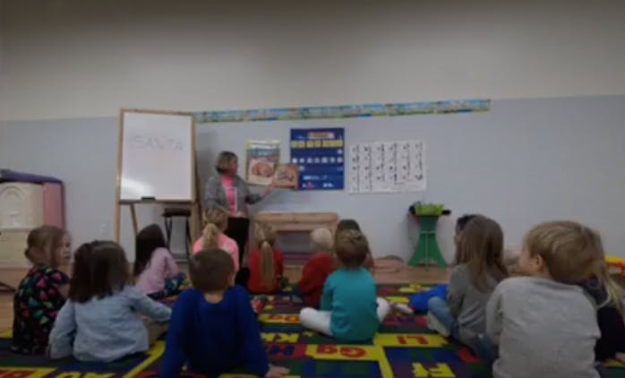 Person reading a book to children in a classroom