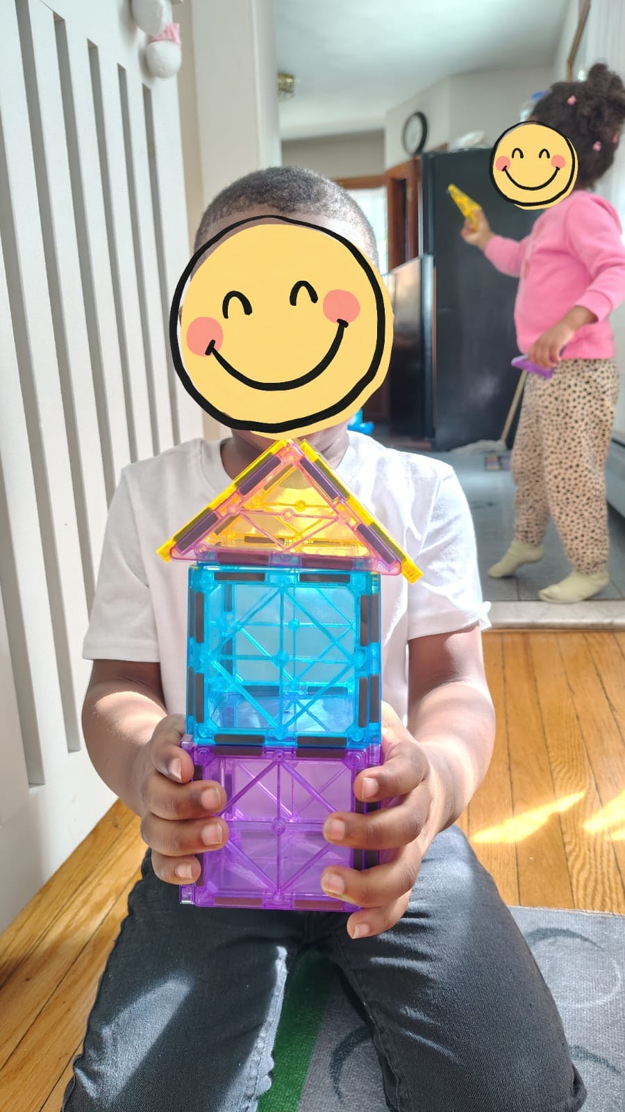 Child holding a structure built with magnetic building tiles