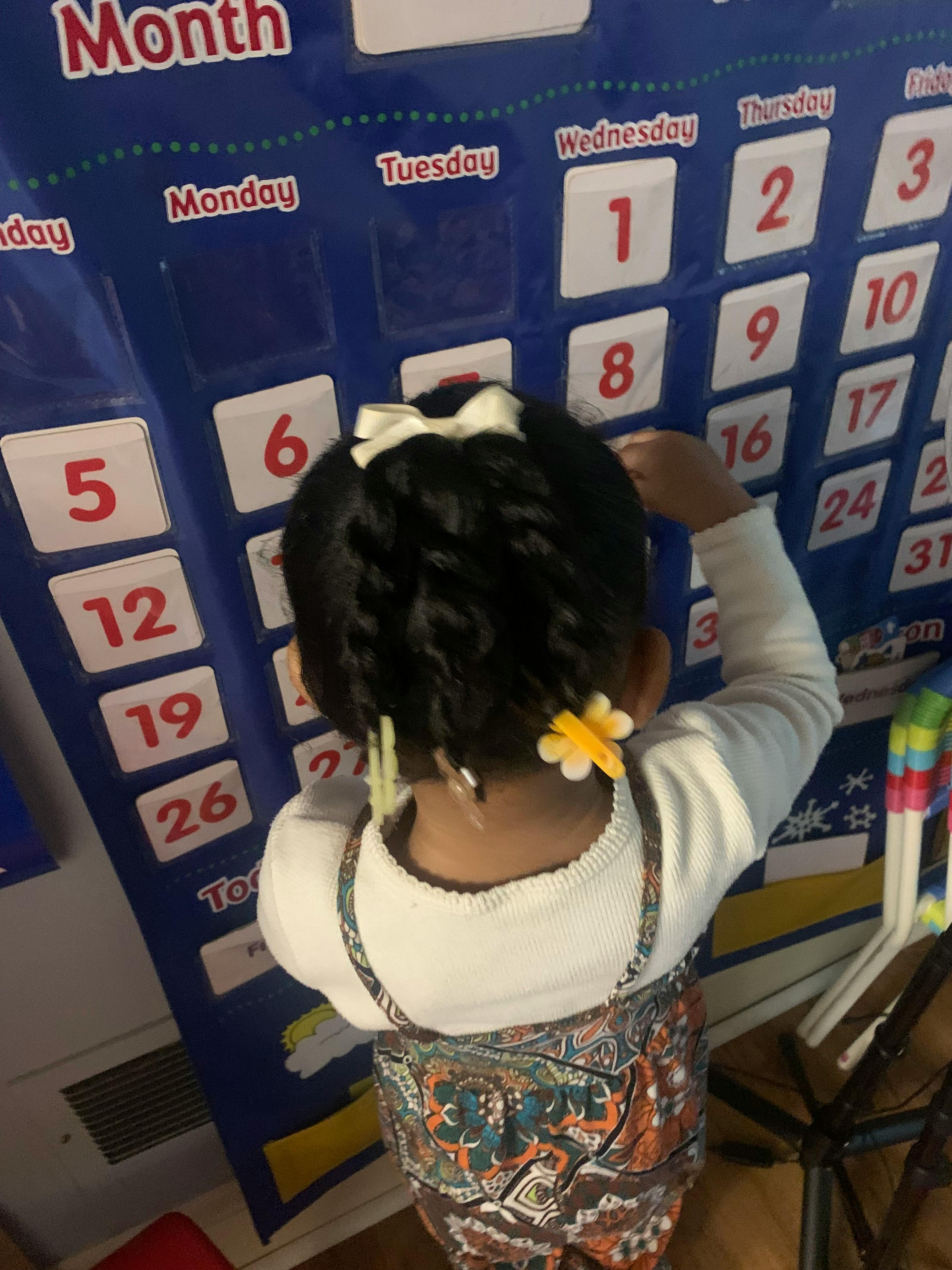 Child placing a number on a blue calendar mat