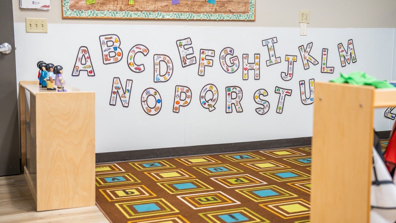 Classroom wall displaying an alphabet chart with a patterned letter rug