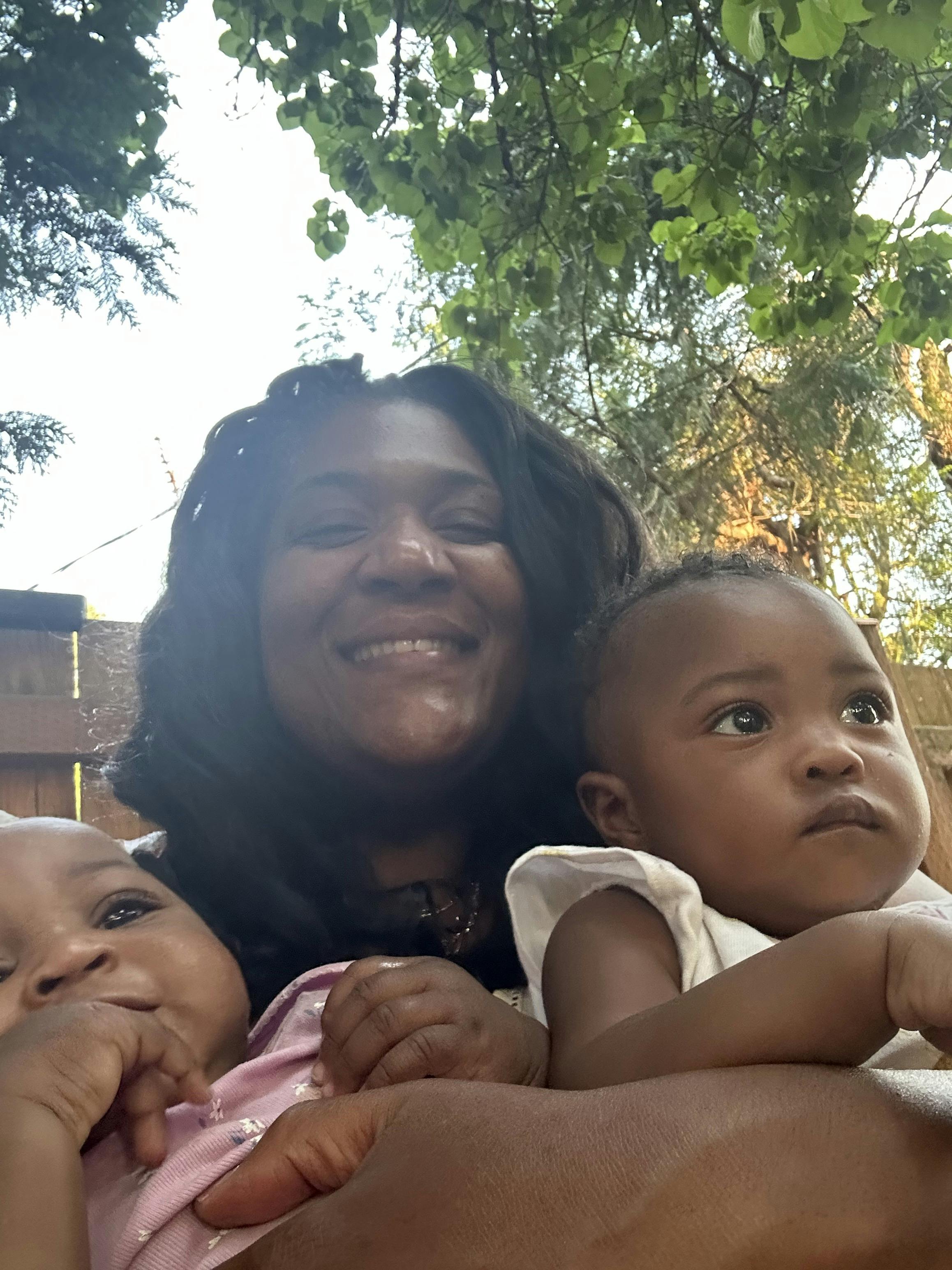 A person holding two children outdoors