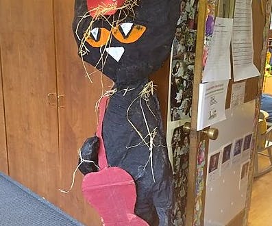 Black cat scarecrow with straw and a red heart