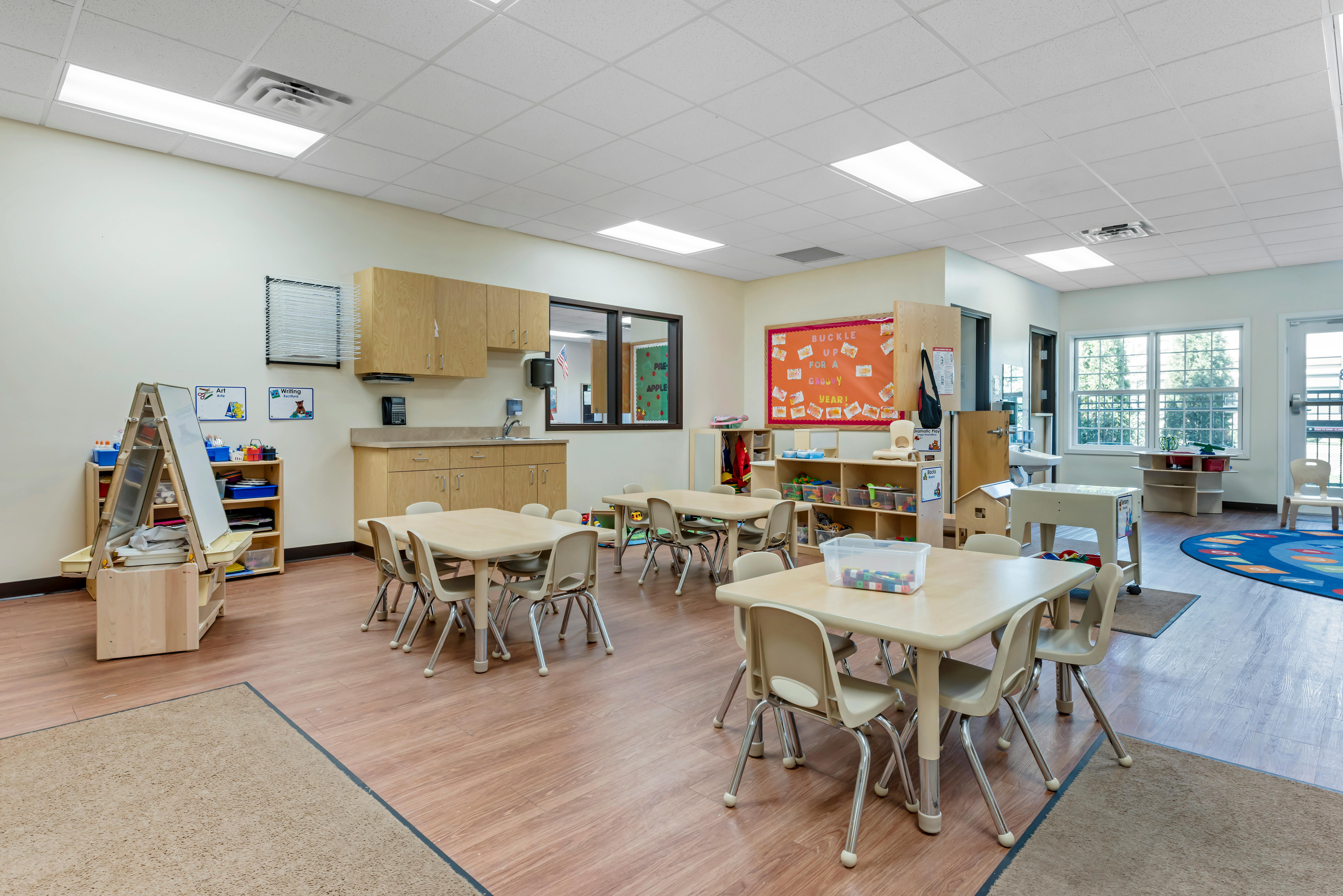 An empty early childhood classroom with small tables and chairs