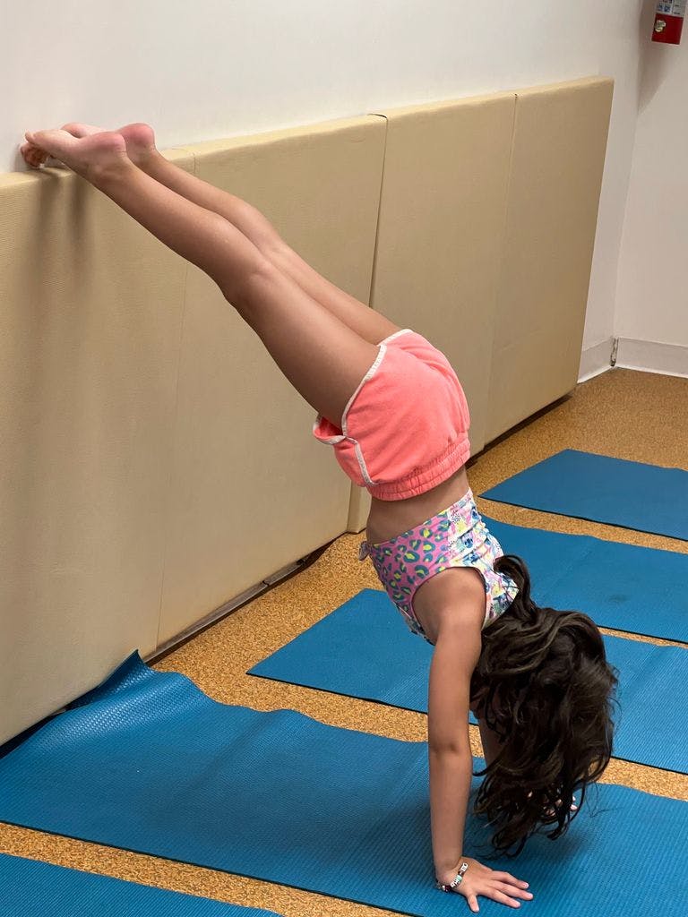 Child doing a handstand against a wall