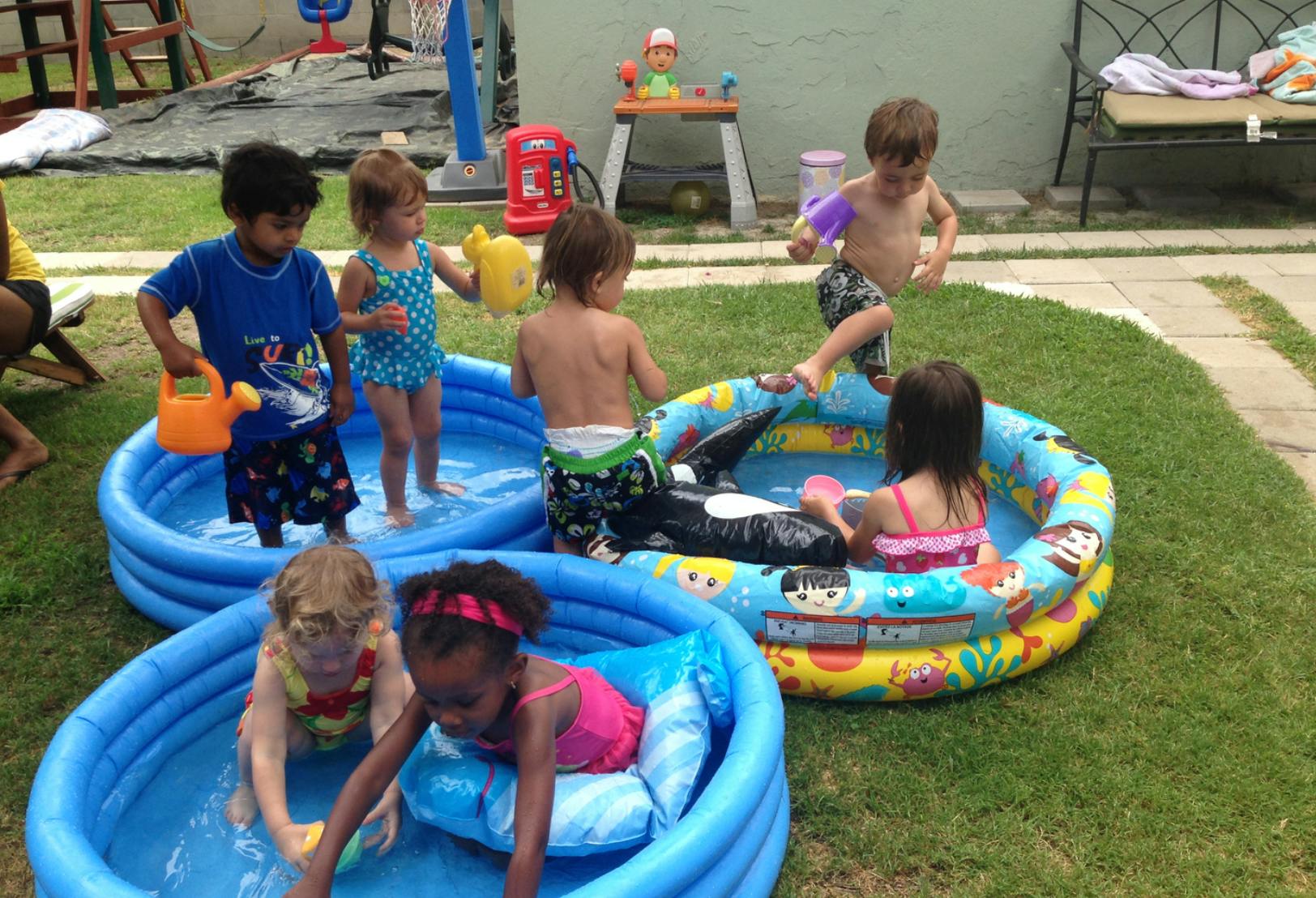 Children playing in multiple inflatable pools outdoors
