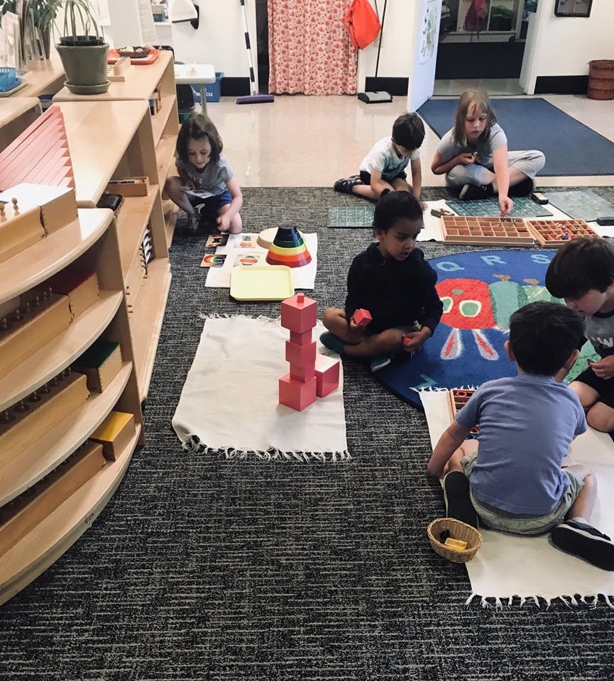 Children sitting on floor playing with blocks and other learning materials