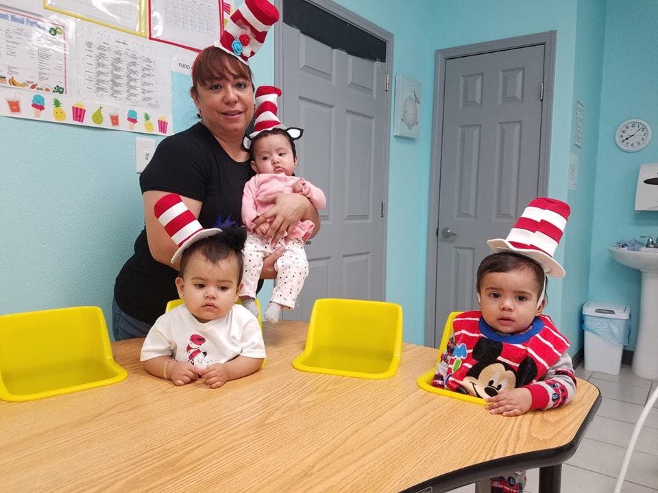 Person holding a child, with two other children at a table, all wearing striped hats
