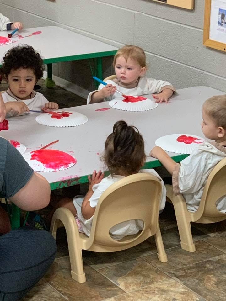 Children painting at a table in a classroom