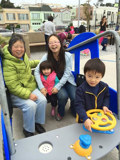 Three people and two children on playground equipment