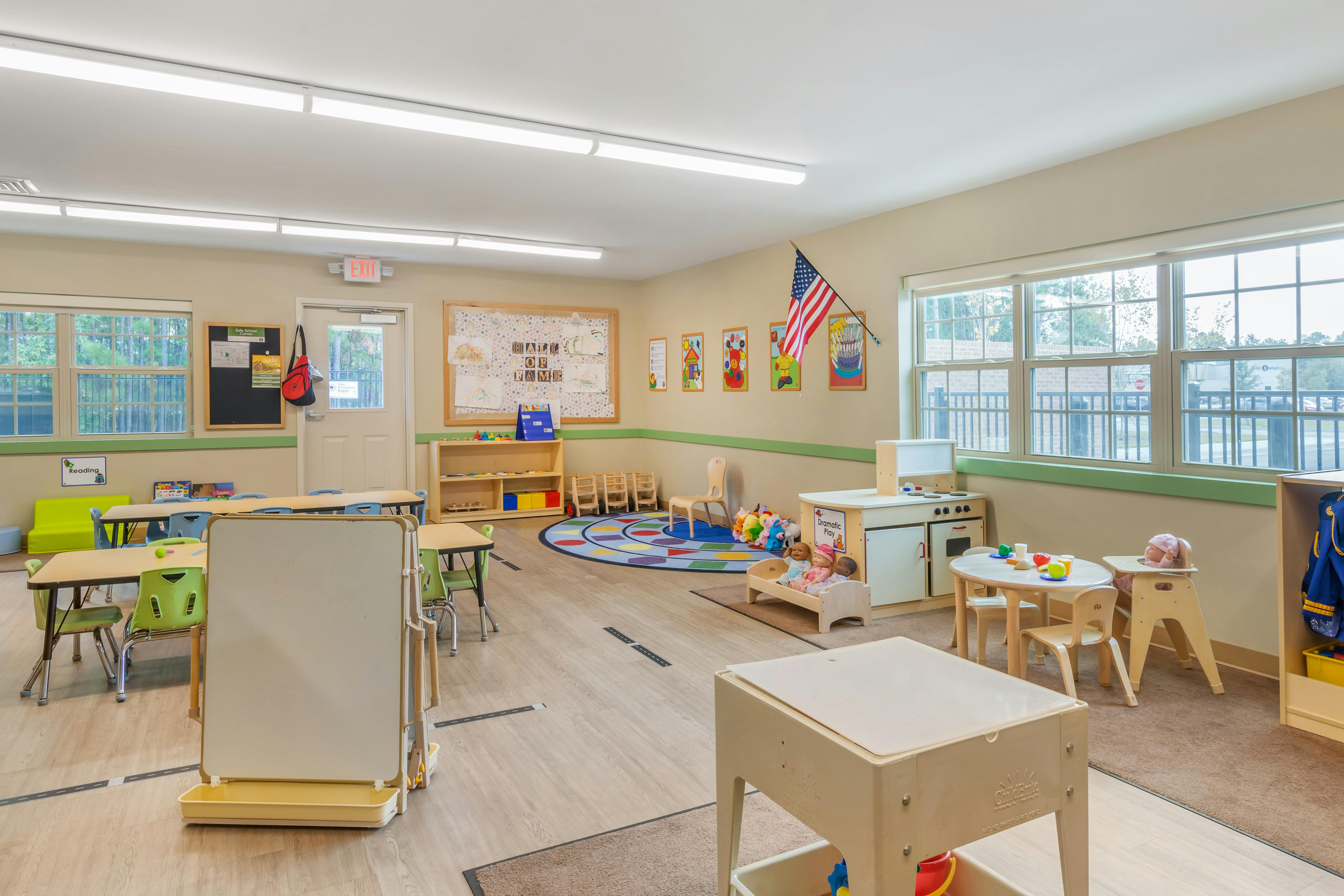 Classroom with tables, chairs, colorful rugs, and play areas