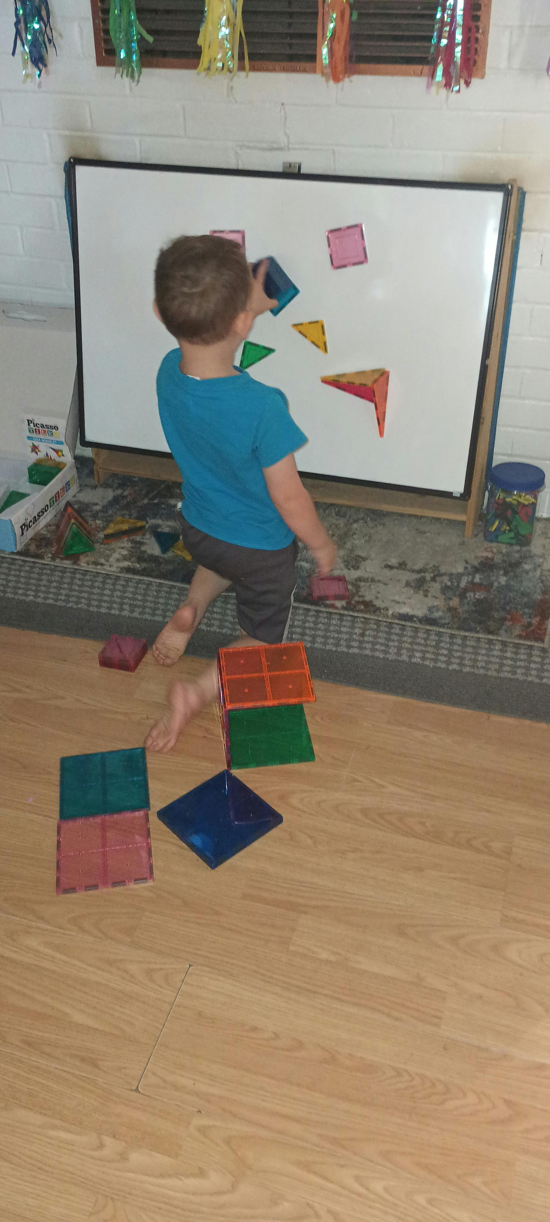 Child playing with magnetic shapes on a whiteboard