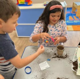Two children planting seeds in a classroom