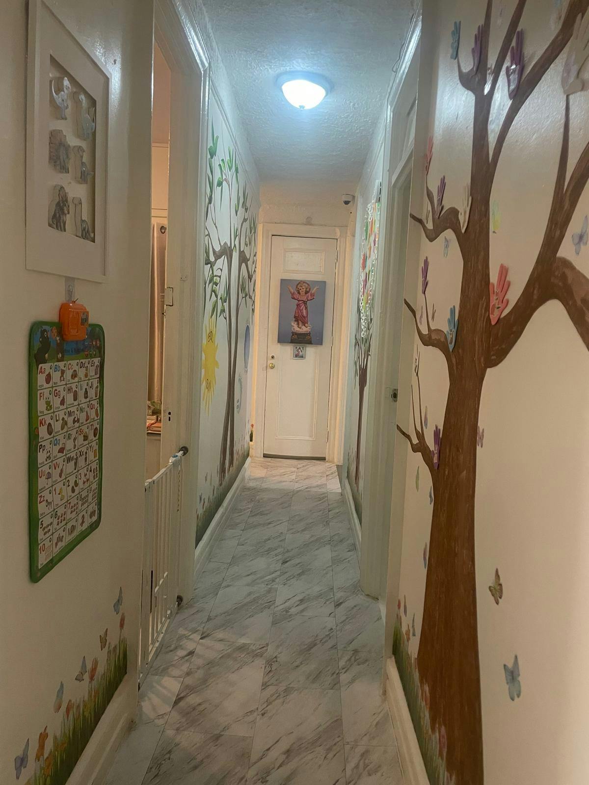 Hallway decorated with painted trees, an alphabet chart, and a baby gate