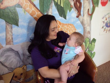Person holding a child in a room with a painted mural