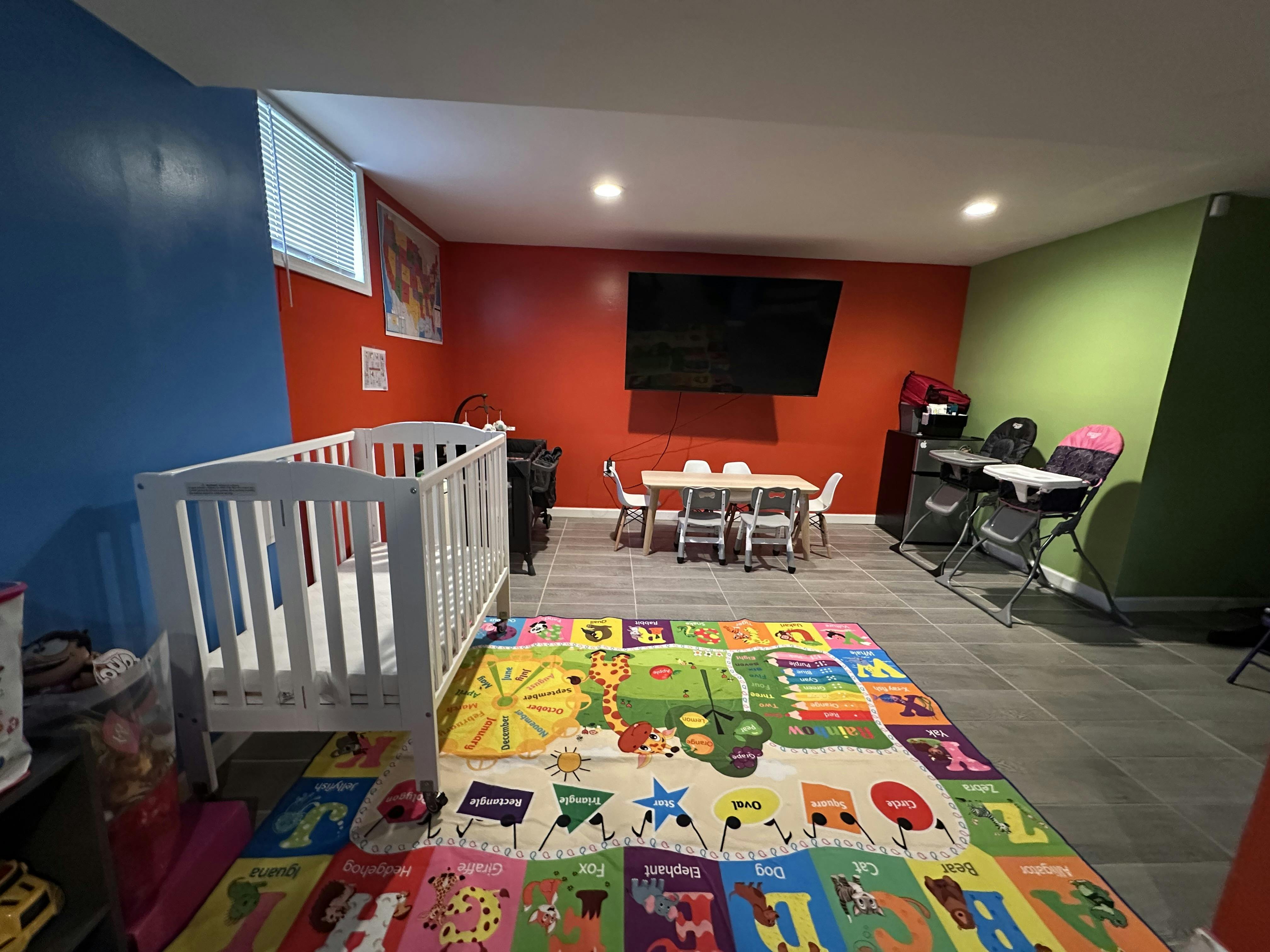 crib, small table and chairs, and playmat in a room with colorful walls