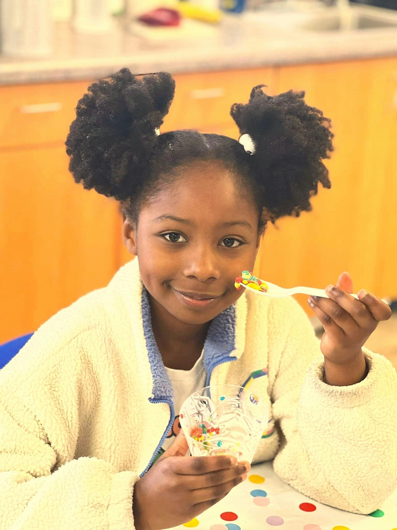 Child holding a cupcake and a fork with sprinkles