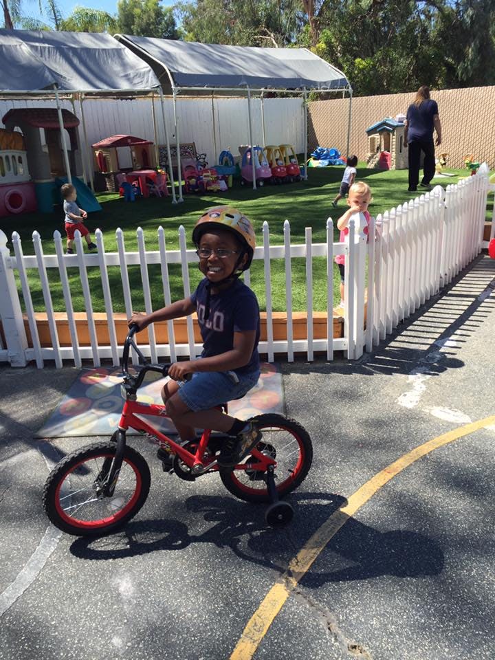 Child in a helmet on a red bicycle with training wheels