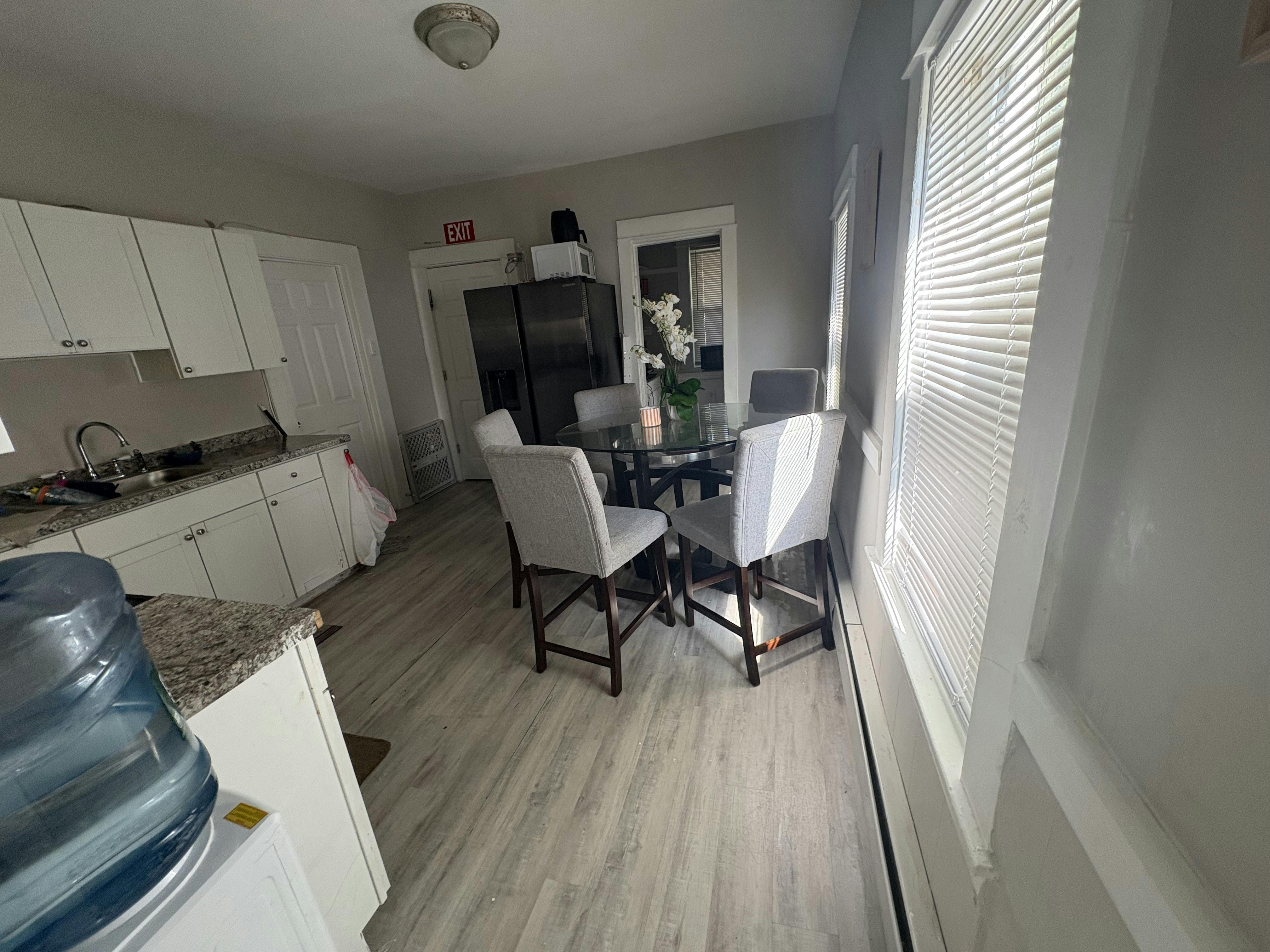 Kitchen with white cabinets and a dining area with a glass table and chairs