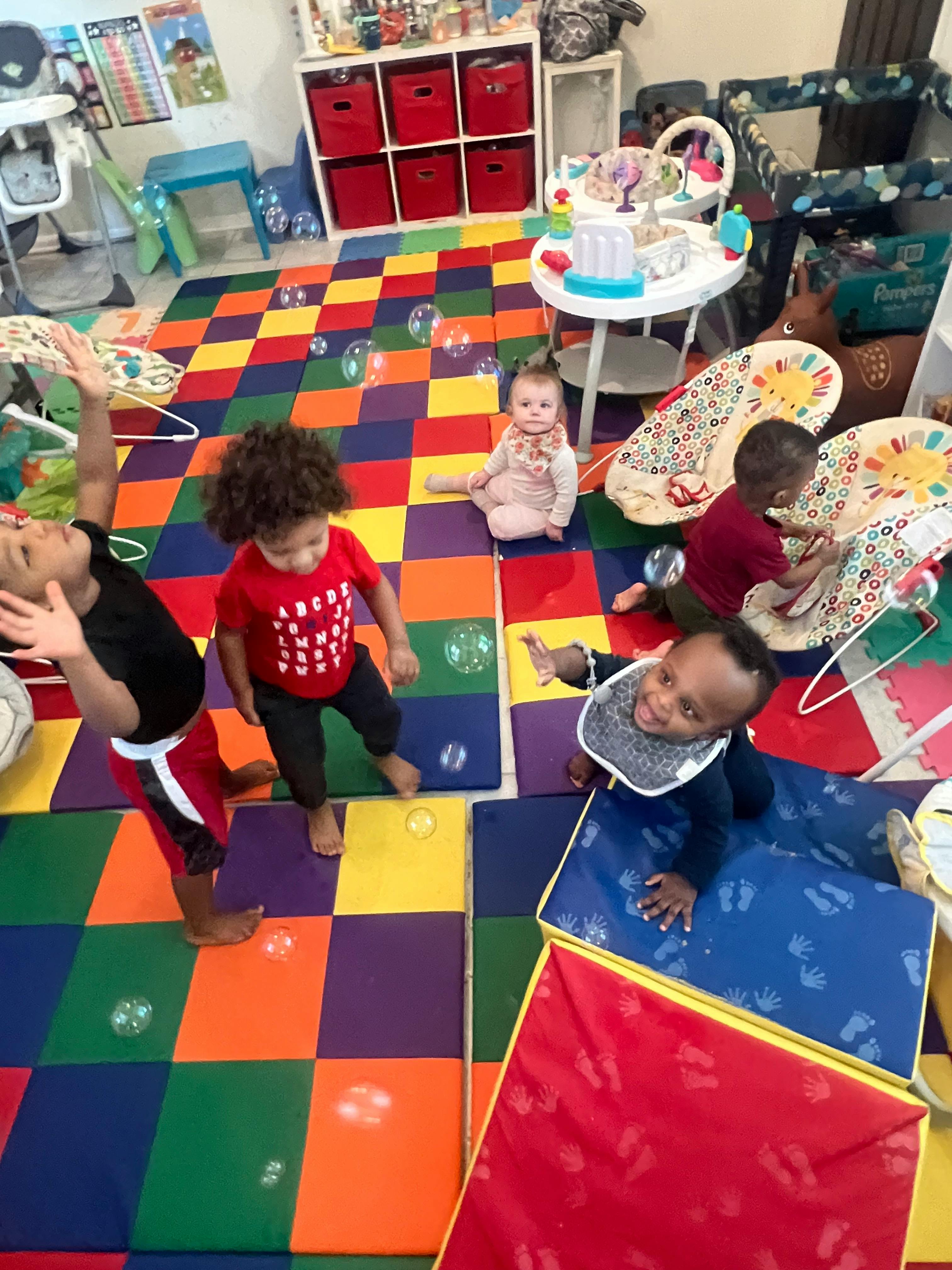 Multiple children playing on a colorful mat with bubbles