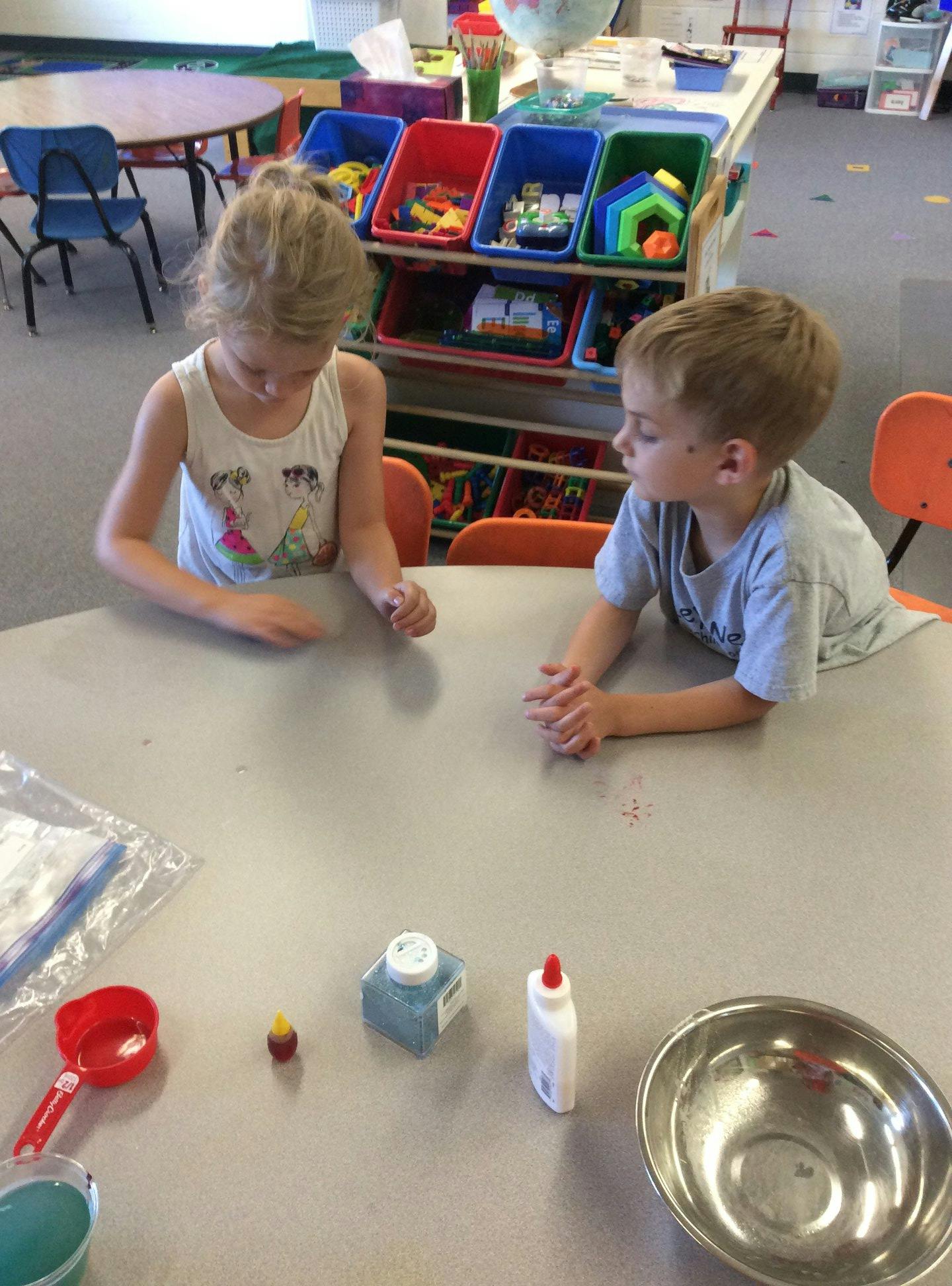 Two children at a table with craft supplies