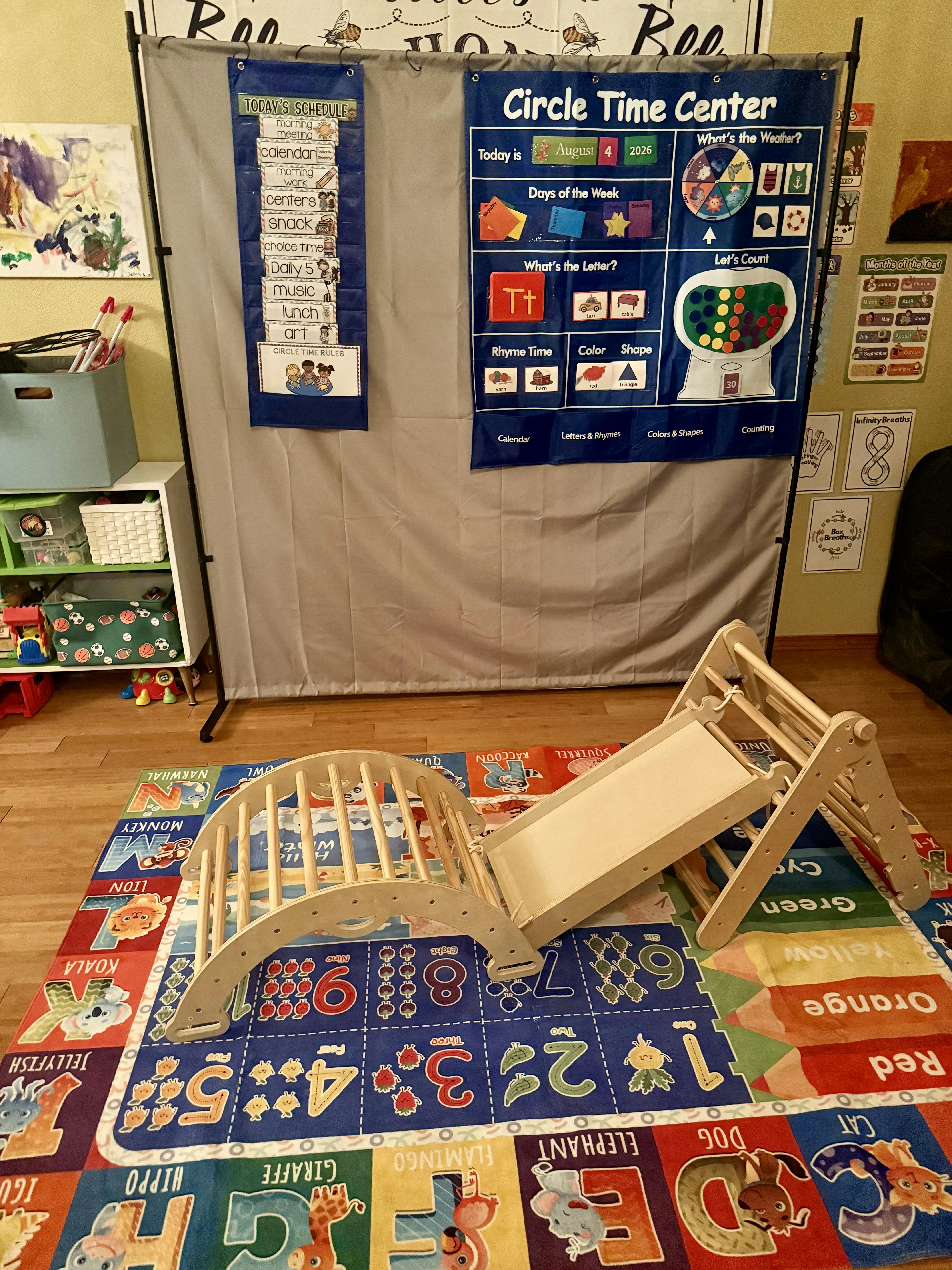 Wooden climbing arch and slide on a colorful alphabet play mat in a classroom