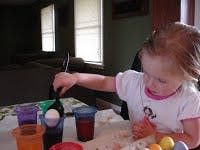 Child dipping an egg into a cup of liquid
