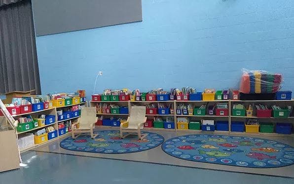 Classroom with shelves of colorful bins and two small rocking chairs on rugs