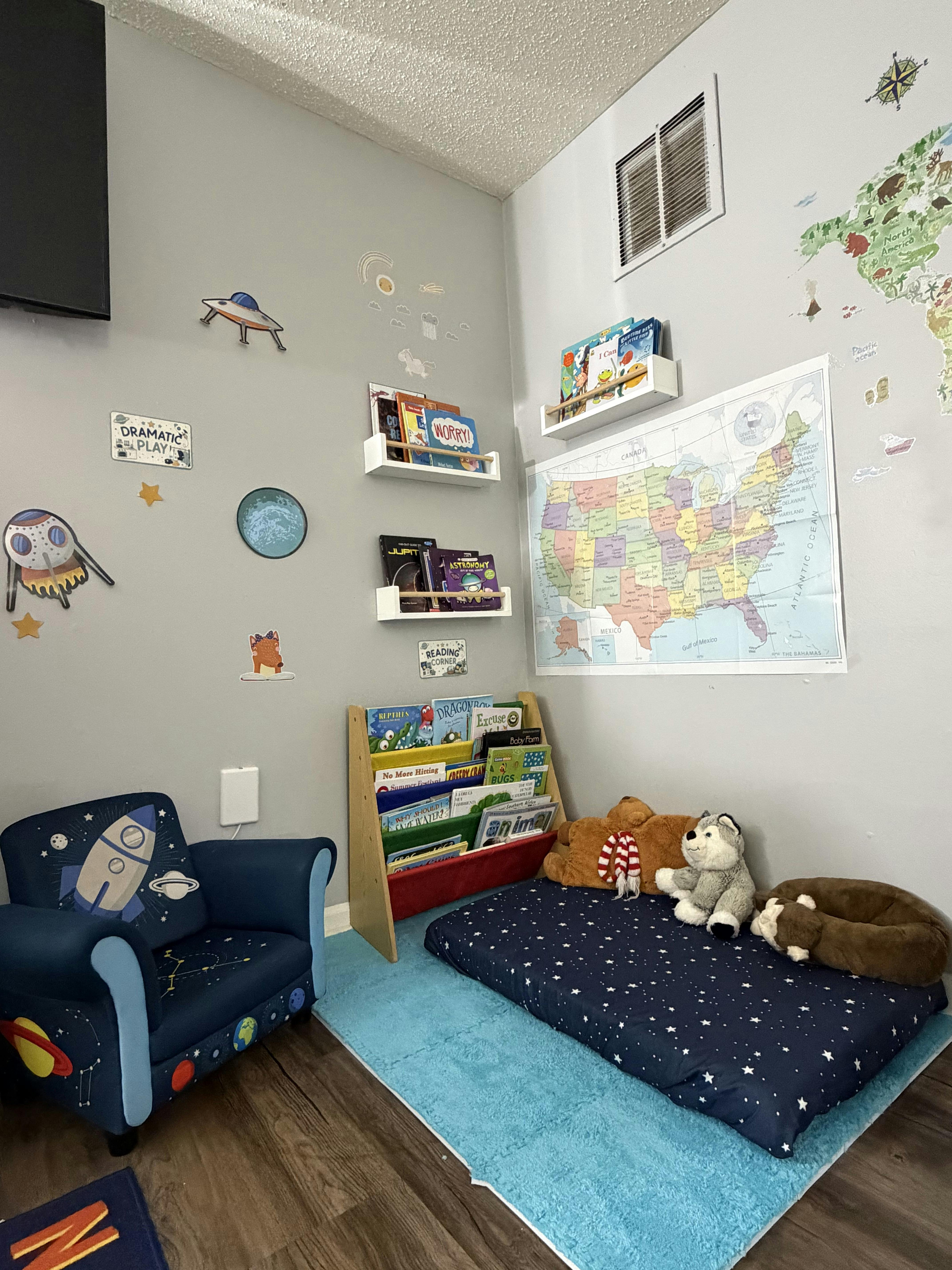 Child reading corner with space-themed chair bookshelves and wall map