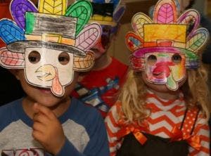 Two children wearing turkey masks