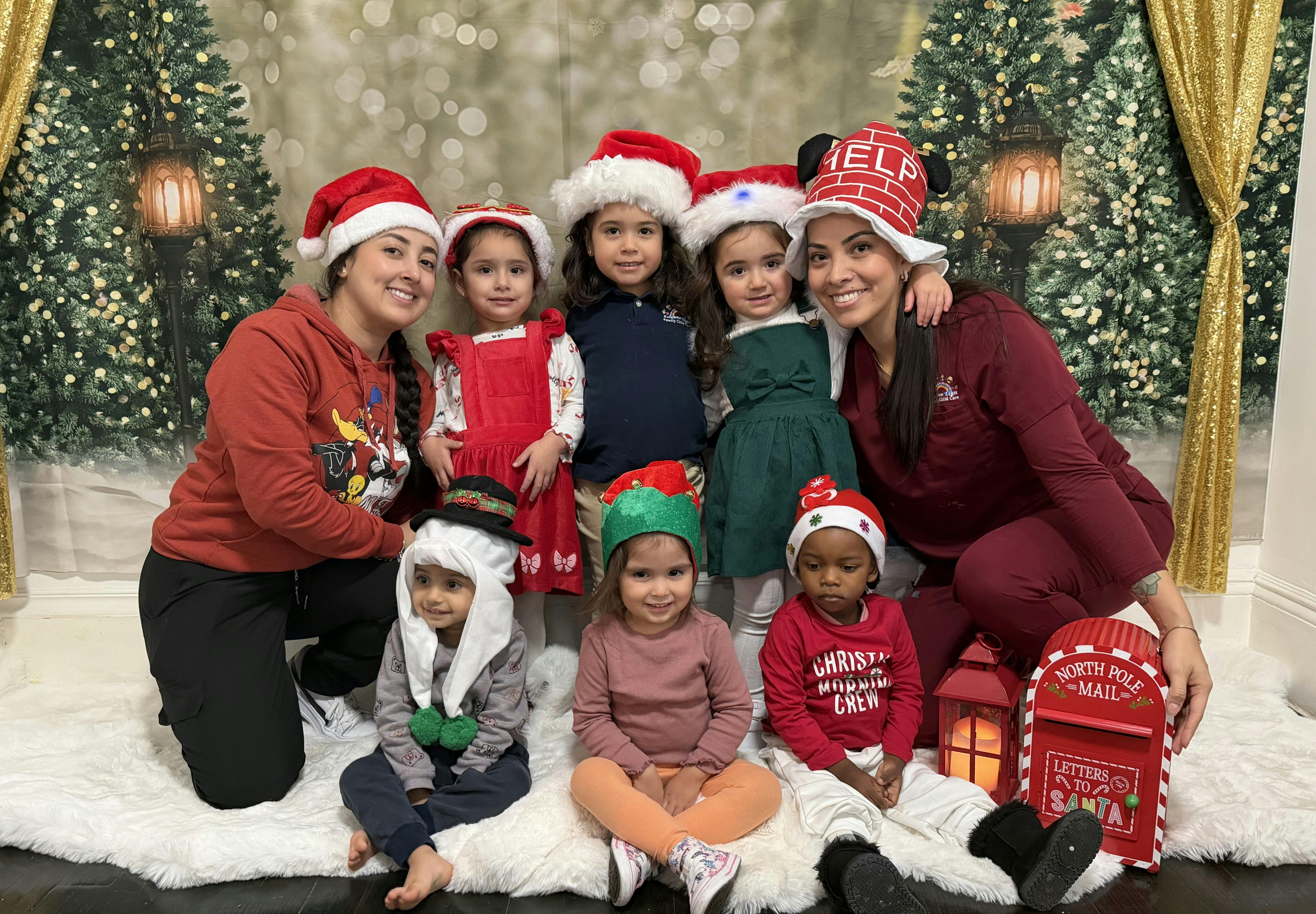 Two people and several children wearing Santa hats and holiday attire