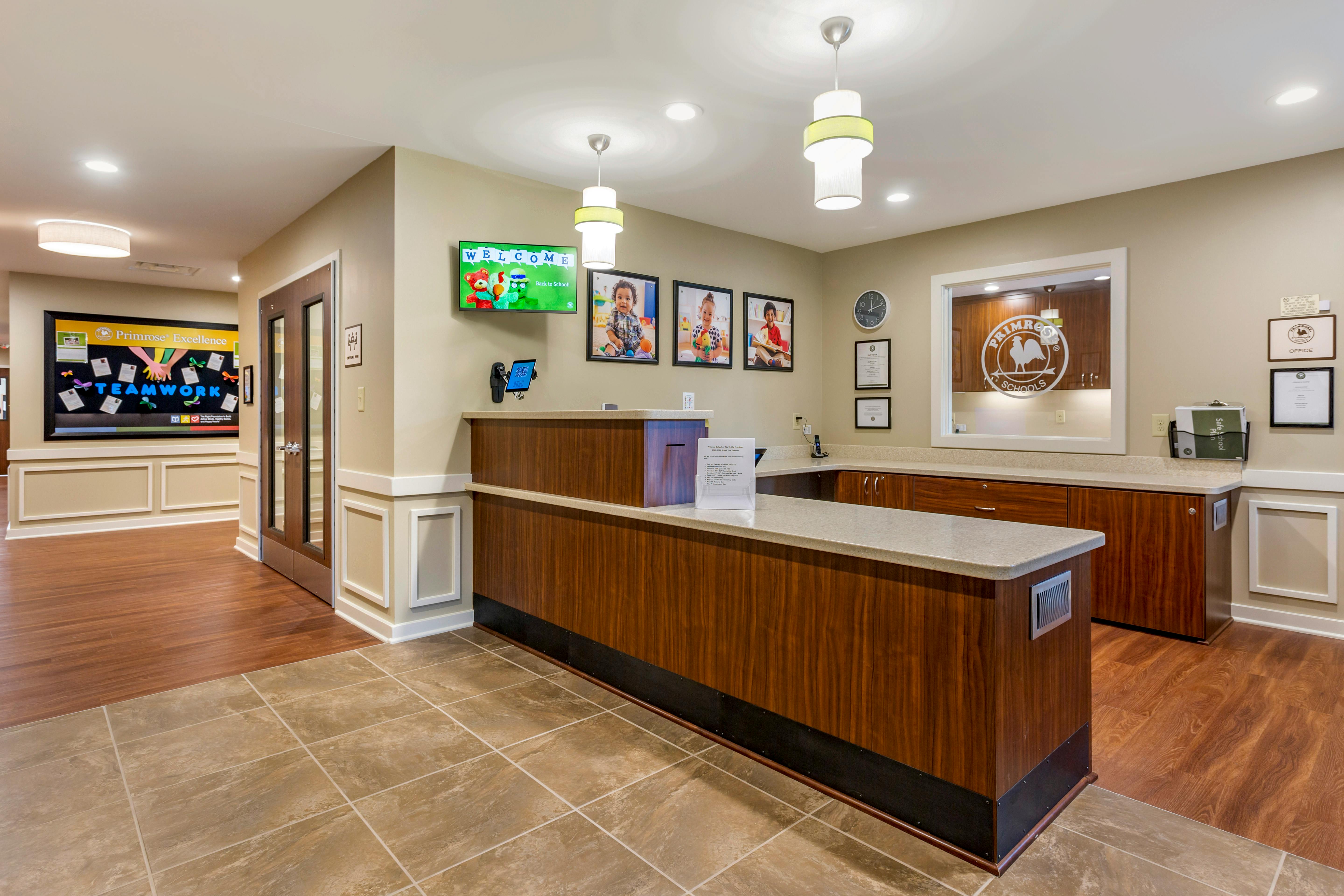 Reception desk with welcome screen and photos of children in a school lobby