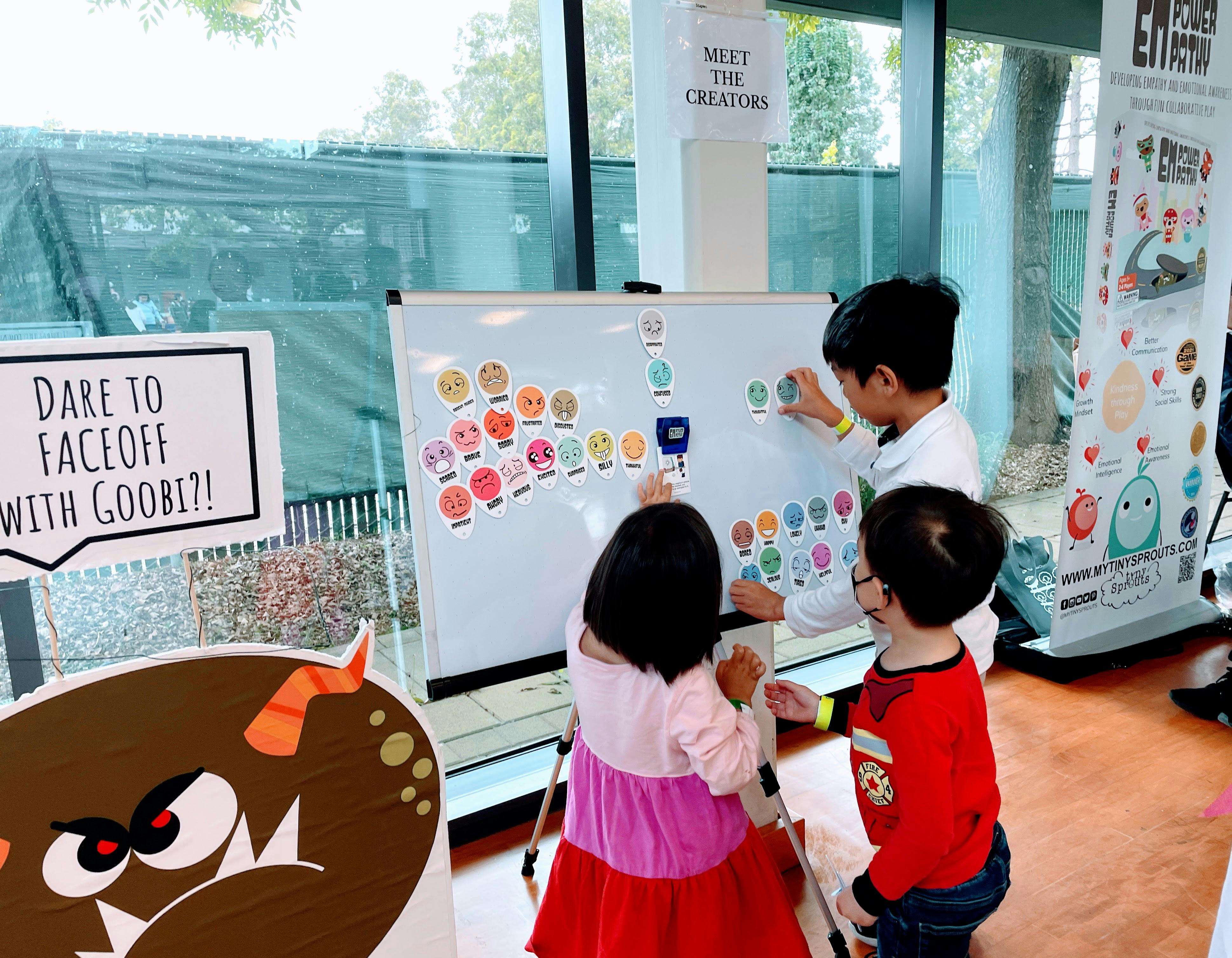 Three children engaging with a whiteboard displaying emotion magnets