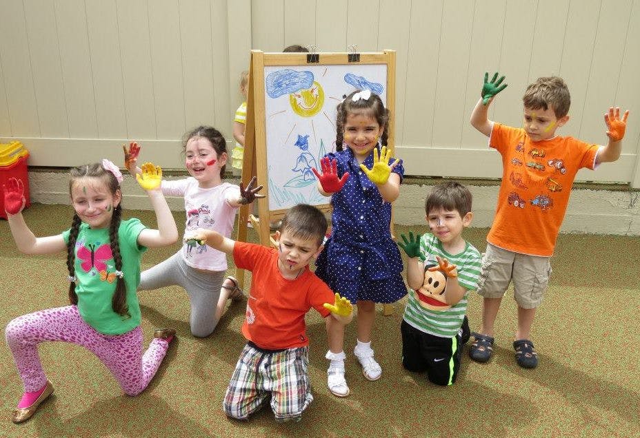 Group of children with paint on their hands in front of an easel