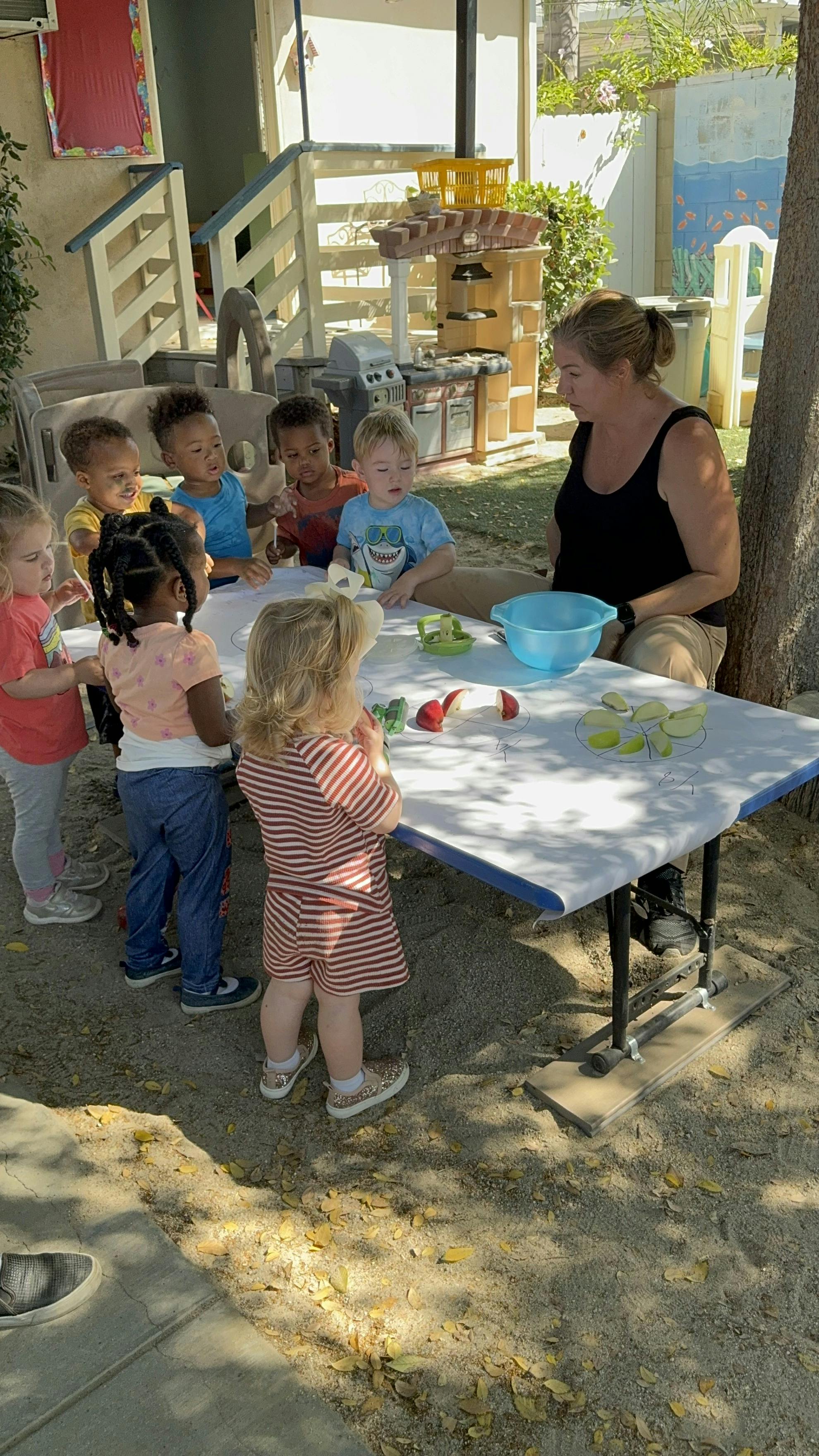 Adult and children gathered around a table with sliced apples on paper