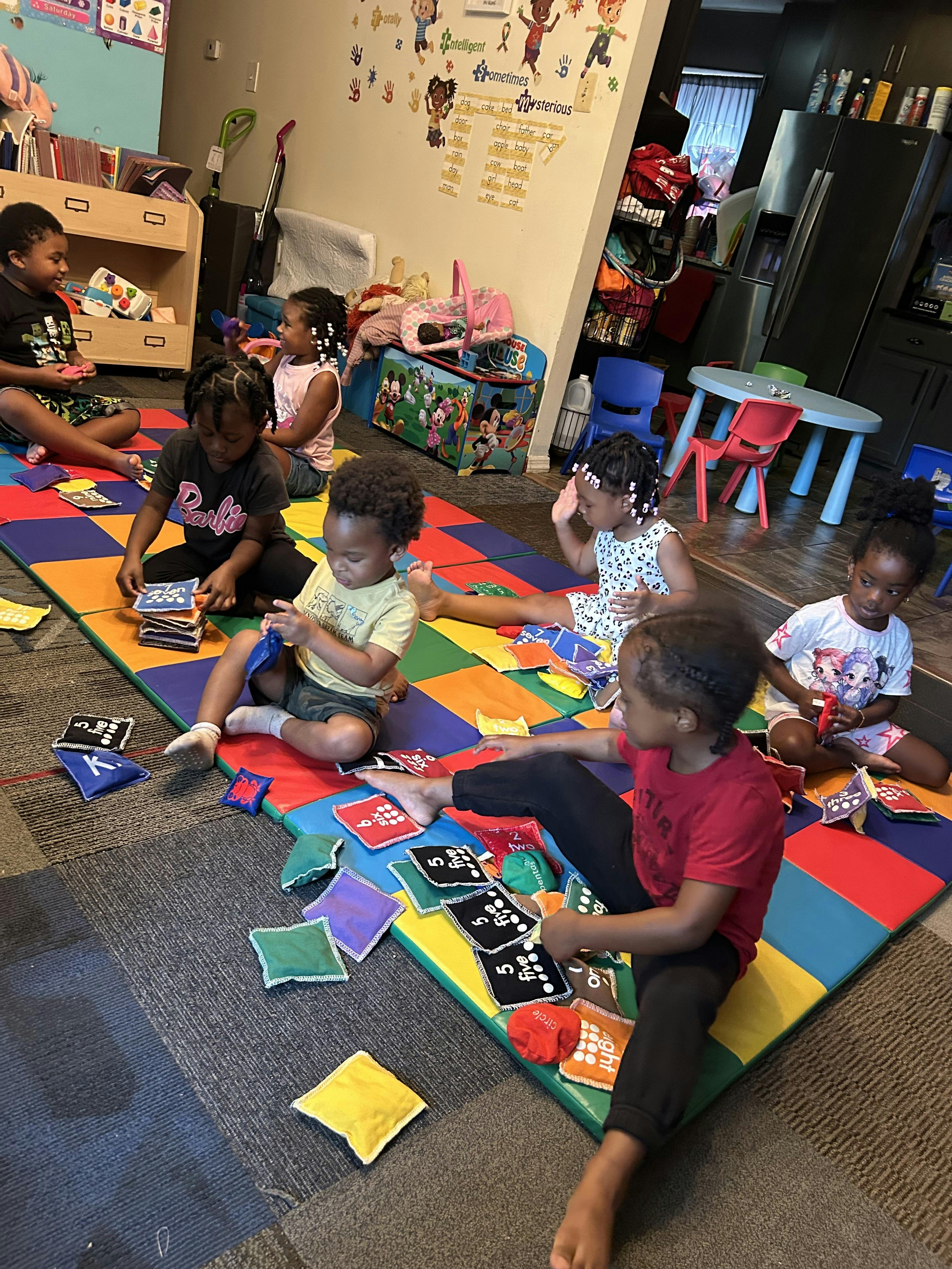 Children sitting on a colorful floor mat playing with small fabric educational bags
