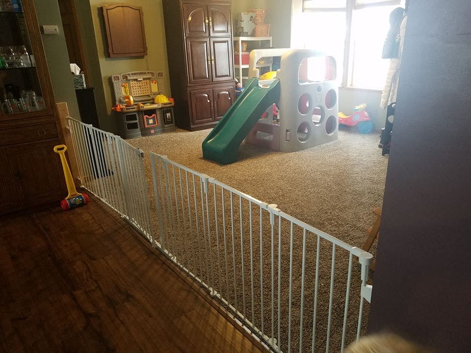 Playpen gate separating a room with a play structure and slide