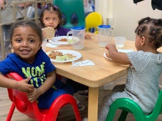 Three children sitting at a table with plates of food