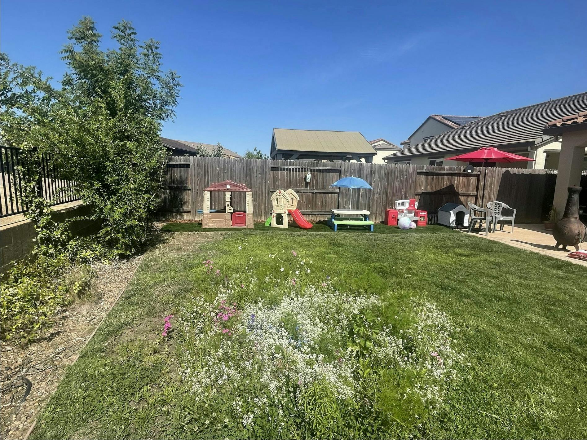 Backyard with playhouses, slide, and picnic table
