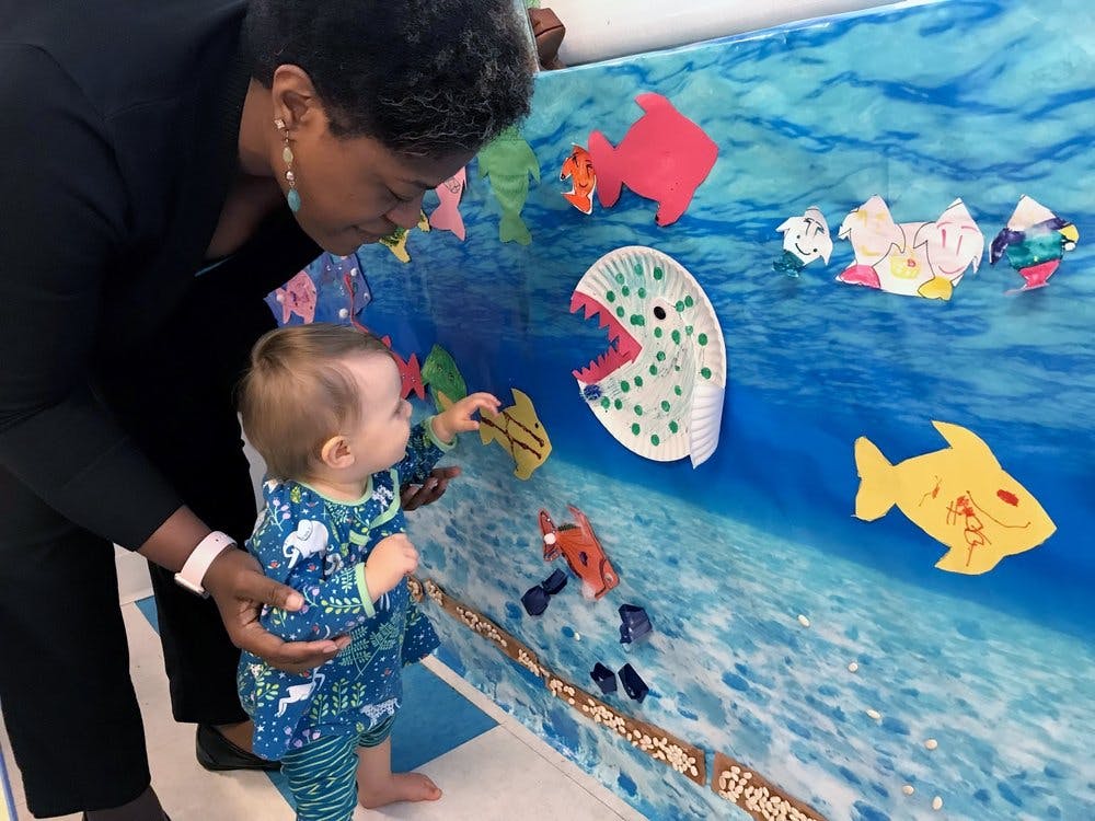 Person and child looking at fish cutouts on a blue wall