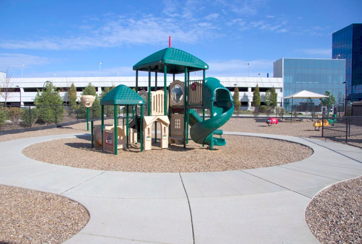 Playground with green and tan play structure and spiral slide