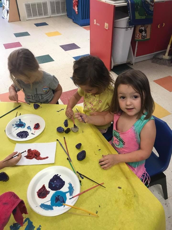 Three children painting at a table