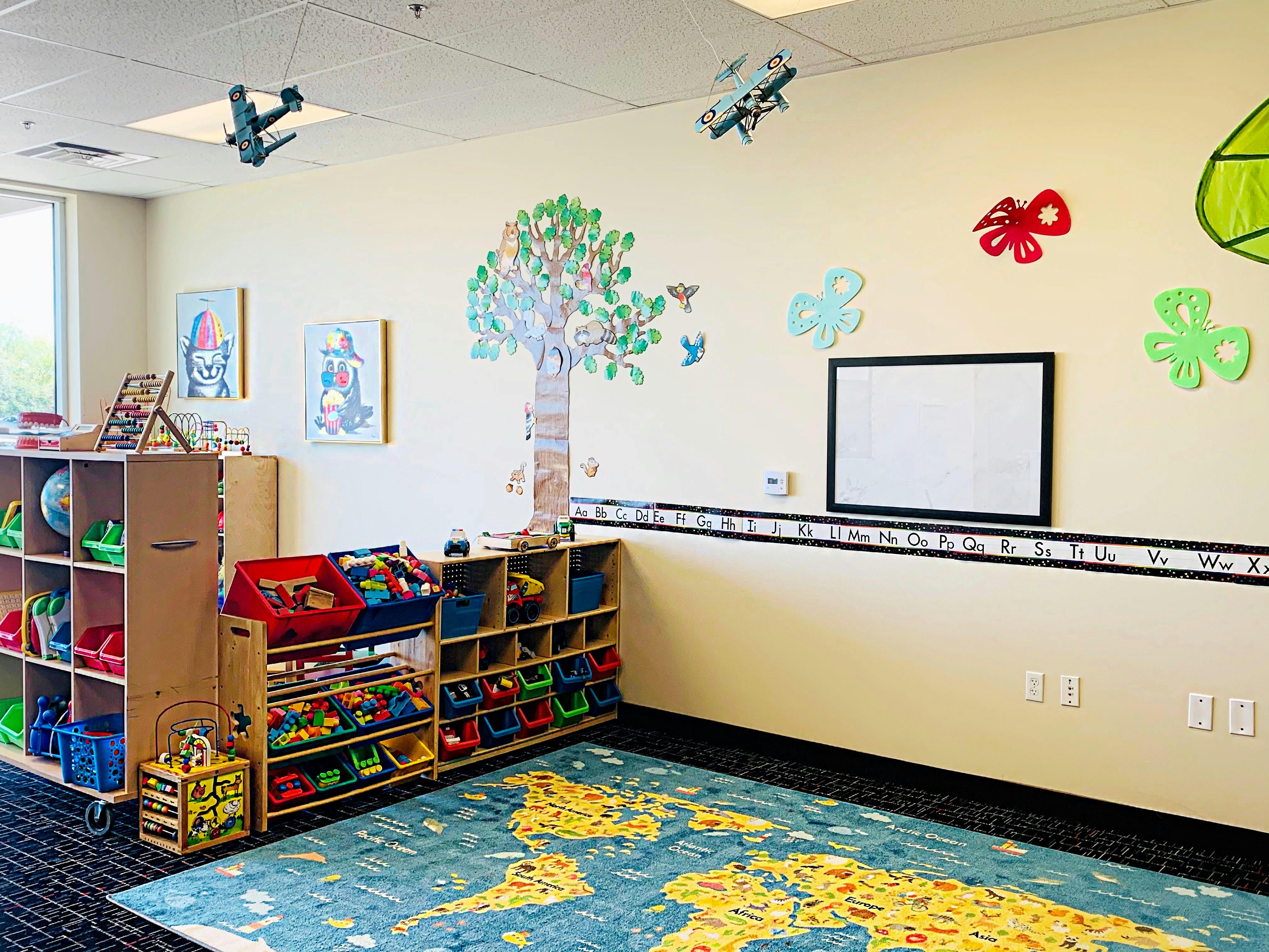 Classroom with toy shelves, world map rug, and wall decorations