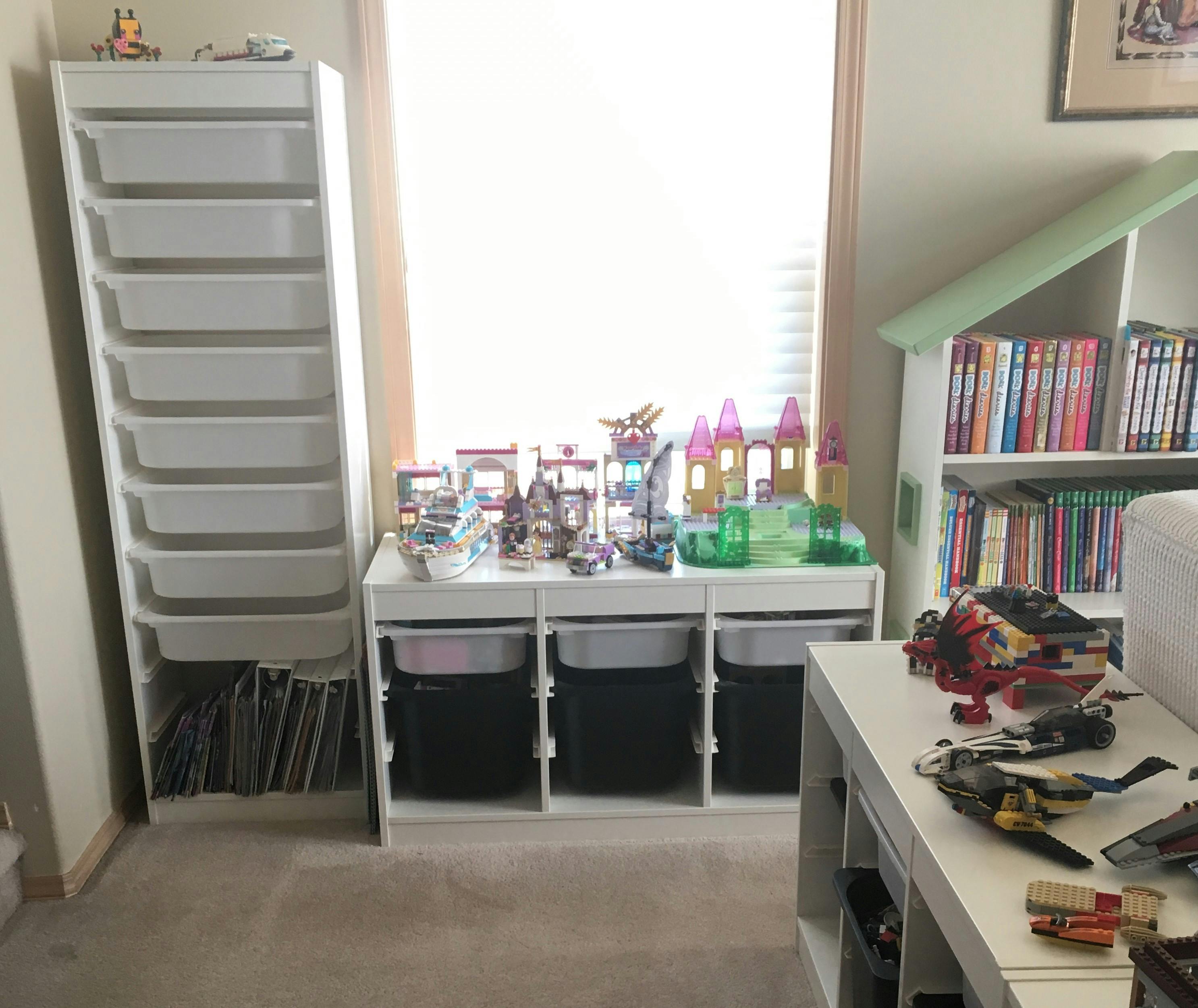 A child's playroom with storage units, toy castles, books, and Lego vehicles